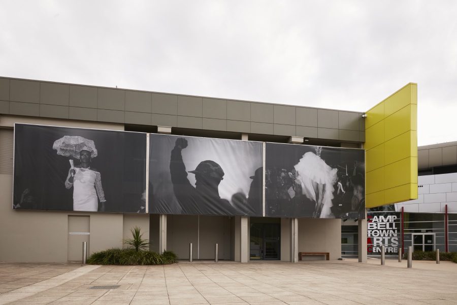 A largescale photographic banner covers the facade of Campbelltown Arts Centre with three images by South African photographer Musa N. Nxumalo depicting South African youth fashion, club and protest culture.
