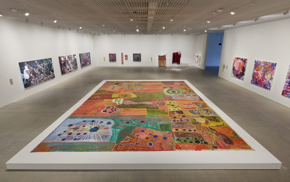 Foreground, left to right: Ngurrara Artists, Ngurrara Canvas II, 1997. Presentation at the 25th Biennale of Sydney was made possible with generous support from the Oranges & Sardines Foundation. Courtesy of the artists and the Ngurrara Canvas Management Group (NCMG) © Ngurrara Artists. Nahom Teklehaimanot, No Shore for the Living, No Shore for the Dead, 2025; The House Forgets my Name, 2025; Only the Cactus is Green, 2025, from the Series ‘This is My Silence, You Name the Sound.’ Commissioned by the Biennale of Sydney. Courtesy of the artist and Circle Art Gallery © Nahom Teklehaimanot. Dindga McCannon, Althea Gibson, First African American to Win Wimbledon 1957, 2012. Courtesy of the Sharjah Art Foundation Collection. Sarah’s Story (South Africa), 2015. Courtesy of the artist and Fridman Gallery. Threads of the Past, Inspiration for the Future, 2000. Courtesy of the artist and Fridman Gallery © Dindga McCannon. Angélica Serech, Mani Kan num na na chire, xa oj ulew (Do not feel so superior, you are dust too), 2025; Chuwa ruxaq q’aq’ (Facing the  Flames), 2025; Aun la sombra si es constante deja huella Autor: Rubén Dario (Even the shadow, if constant, leaves a mark Author: Rubén Dario), 2025. Commissioned by the Biennale of Sydney and the Fondation Cartier pour l’art contemporain. Courtesy of the artist and La Galeria Rebelde © Angélica Serech. Yaritji Young, Tjala Tjukurpa III, 2025; Tjala Tjukurpa II, 2025. Commissioned by the Biennale of Sydney with generous support from the South Australian Government through CreateSA. Courtesy of the artist and Tjala Arts © Yaritji Young. Installation view, 25th Biennale of Sydney, Rememory, 2026, Art Gallery of New South Wales. Photo © Art Gallery of New South Wales, Felicity Jenkins.